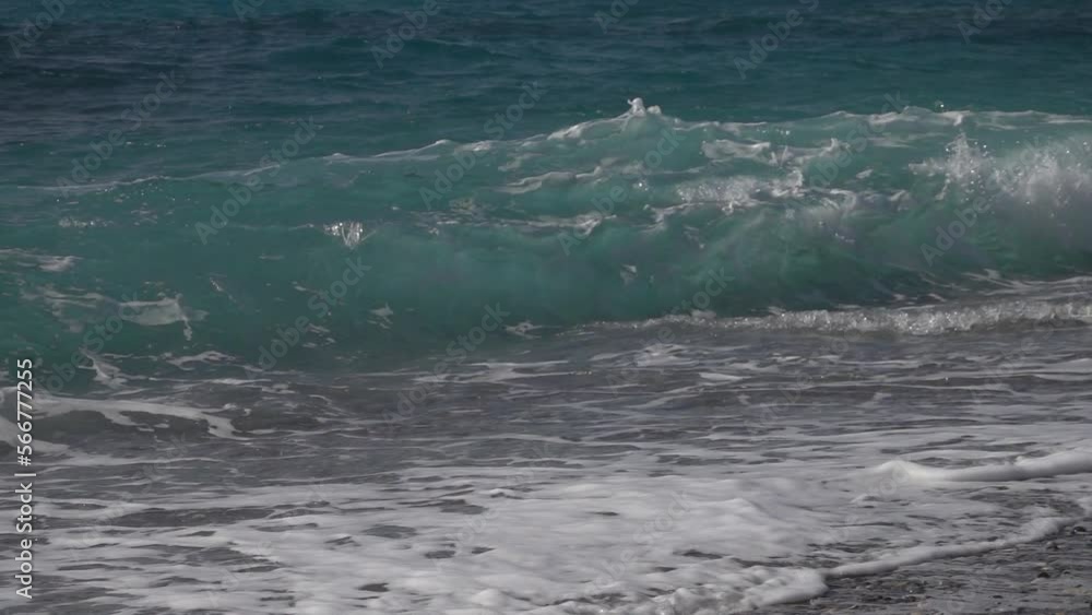 Slow motion blue ocean wave breaking against a stony beach. Slow motion blue ocean wave breaking against a stony beach.