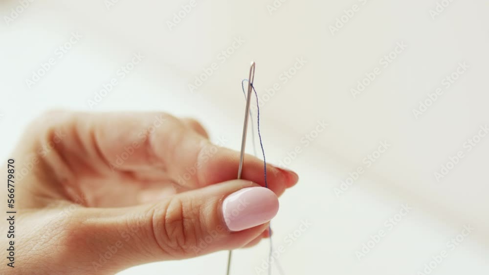 Clothing designer hands pulling thread into the eye of a sewing needle. Sew work and handmade hobby. Clothing designer hands pulling thread into the eye of a sewing needle. Sew work and handmade hobby.