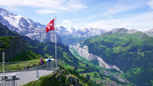 Swiss flag waving, tourists admire peak of Jungfrau mountain on Mannlichen viewpoint, Bernese Oberland in Switzerland photo