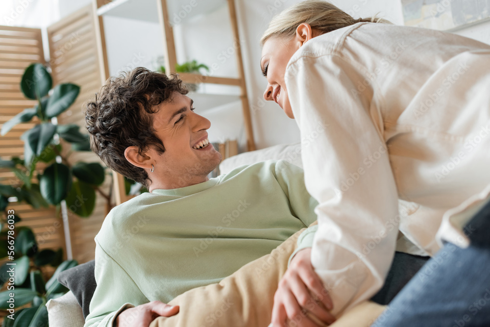 happy young couple smiling while having pillow fight in living room. happy young couple smiling while having pillow fight in living room.