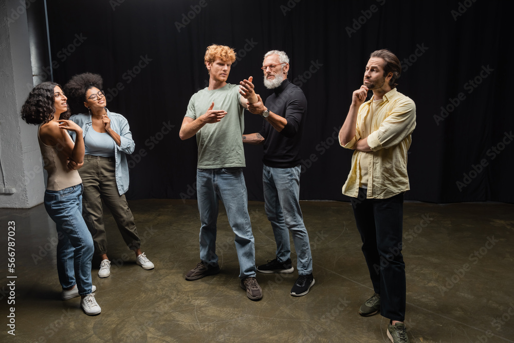 mature art director assisting redhead man during rehearsing near emotional interracial actors. Translation of tattoo: kanji, danger.