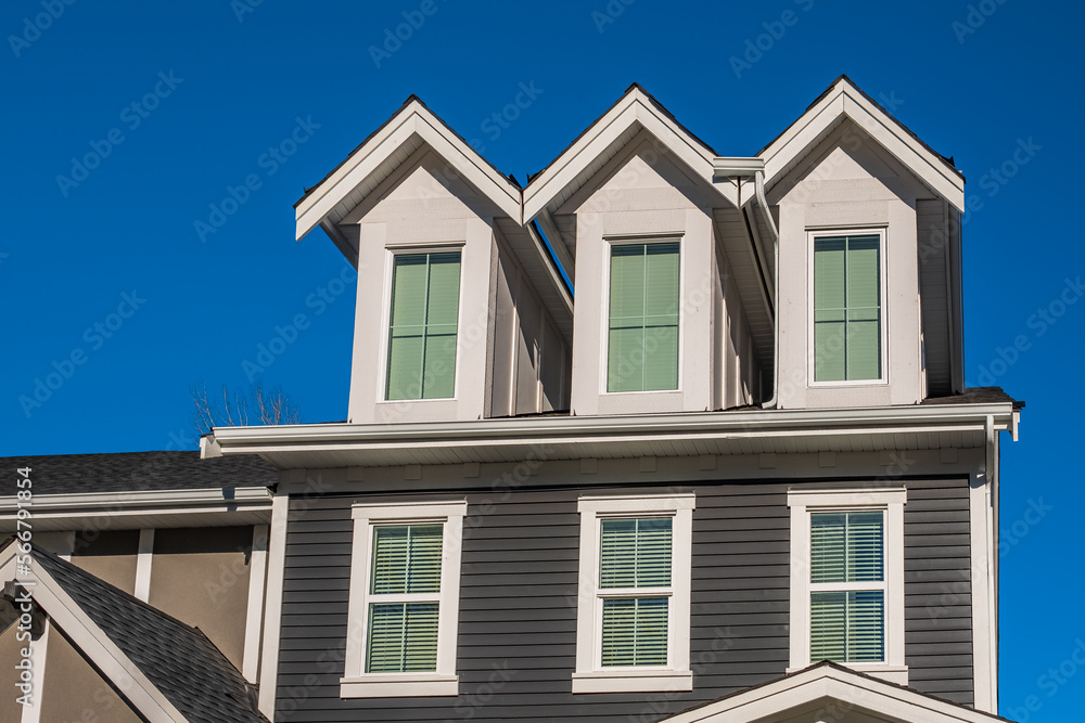 Top of a house with nice windows. Dormer and a blue sky. Real Estate Exterior Front House in a residential neighborhood