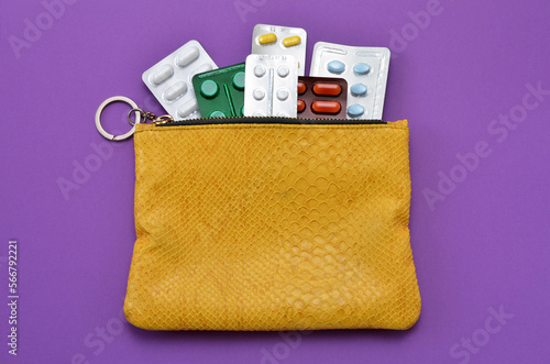 different pills in a yellow bag on a purple background, flat lay