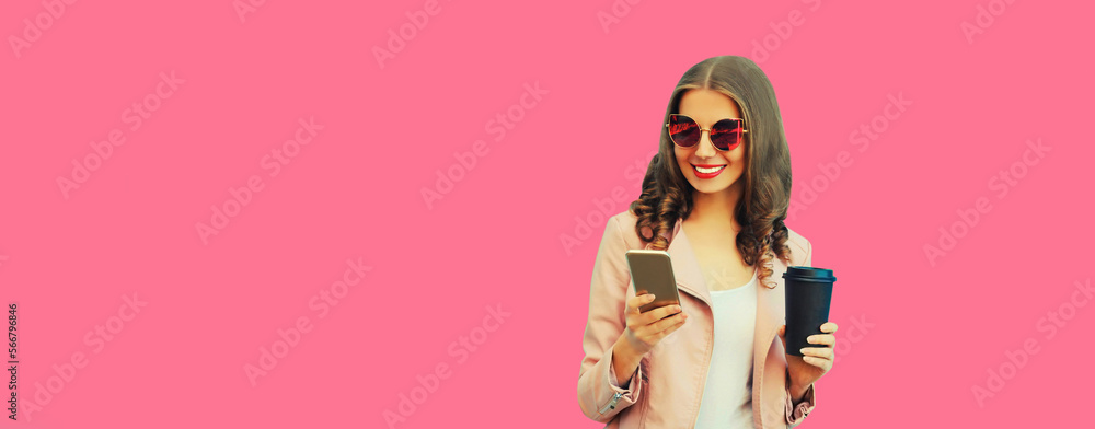 Portrait of beautiful happy smiling young woman with smartphone wearing pink sunglasses on pink background, blank copy space for advertising text