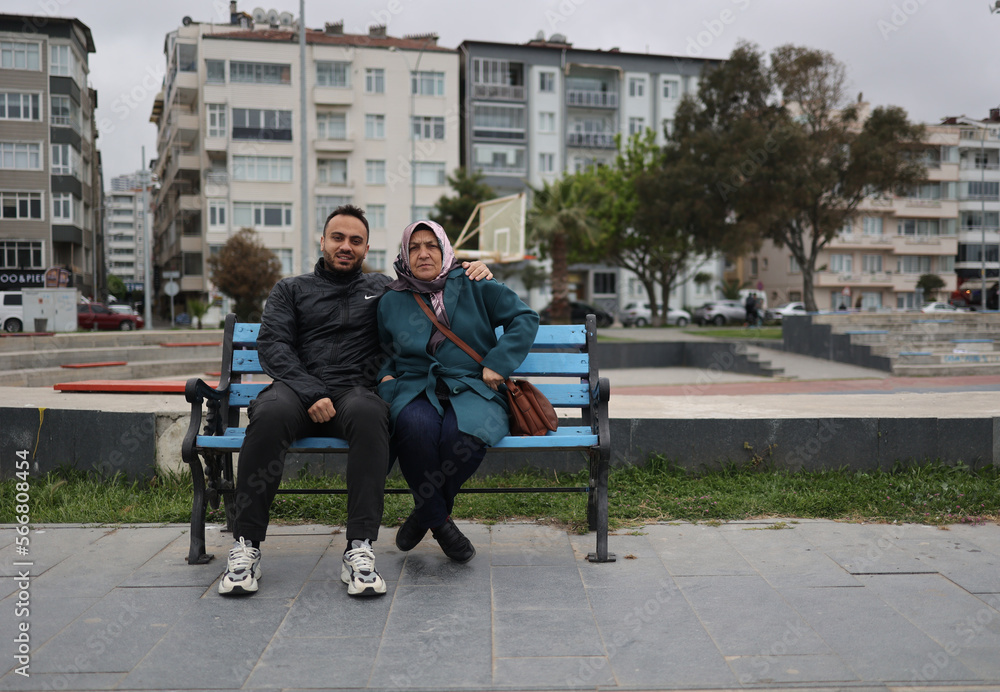 Obraz premium The mother and her son are sitting on the bench.