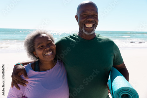 Cheerful african american senior couple spending vacation at beach against sea and clear sky