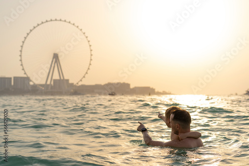Photography Dad and son swim in the sea with views of Dubai in the background