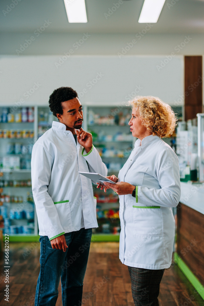 Obraz premium Diverse pharmacists using digital tablet in pharmacy.