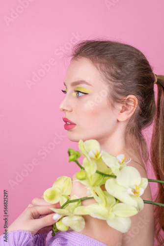 Young woman with spring make up holding flowers isolated on pink background Close up portrait Beauty and fashion concept