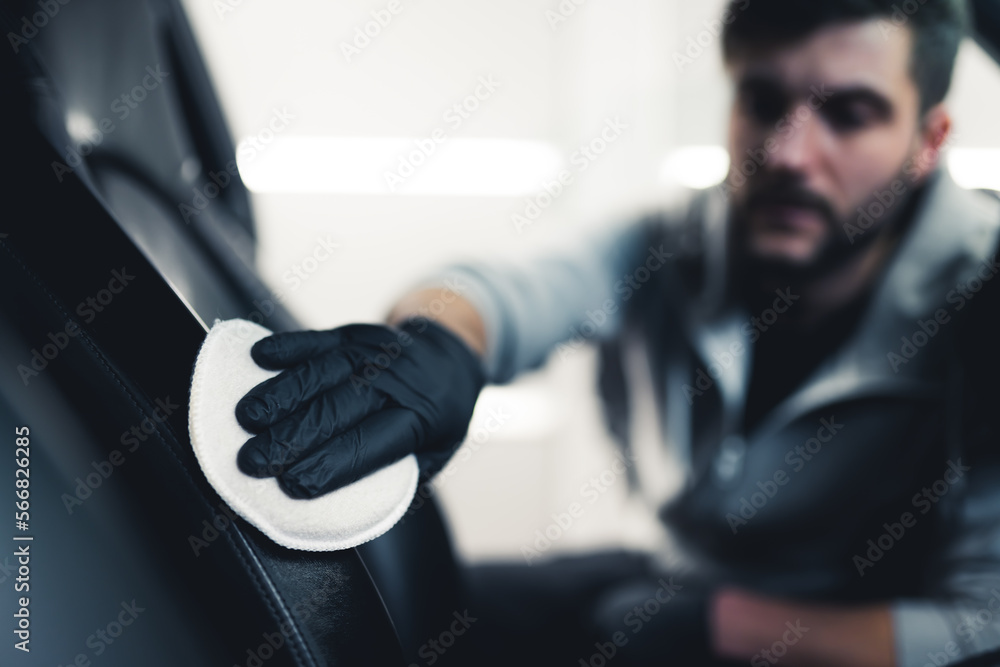 Man cleaning and washing car interior with cotton pad. Blurred mechanic in the background. Car detailing concept. High quality photo Man cleaning and washing car interior with cotton pad. Blurred mechanic in the background. Car detailing concept. High quality photo