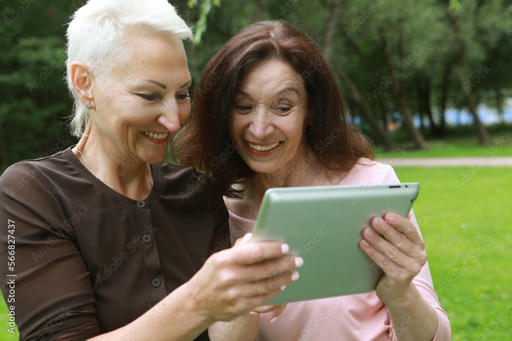 Two happy old women laugh merrily and look at the screens of tablet. Two happy old women laugh merrily and look at the screens of tablet.