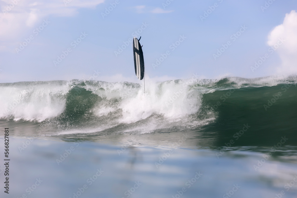Surfboard over splashing wave in sea against sky Surfboard over splashing wave in sea against sky