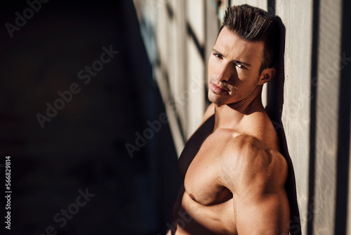 handsome muscular man leaning against the wall looking at camera photo