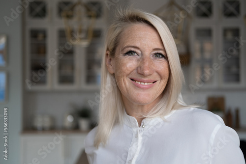 Smiling confident stylish mature middle aged woman standing at home office.