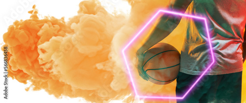 Midsection of biracial basketball player holding ball with hexagon over smoky background