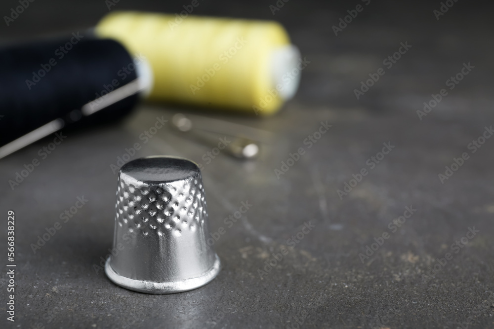 Silver sewing thimble on grey table, closeup. Space for text