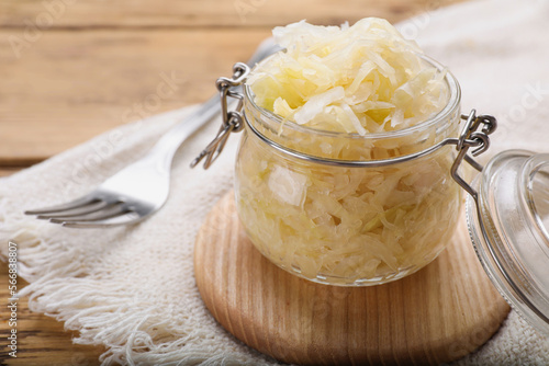 Glass jar of tasty sauerkraut on wooden table, closeup. Space for text