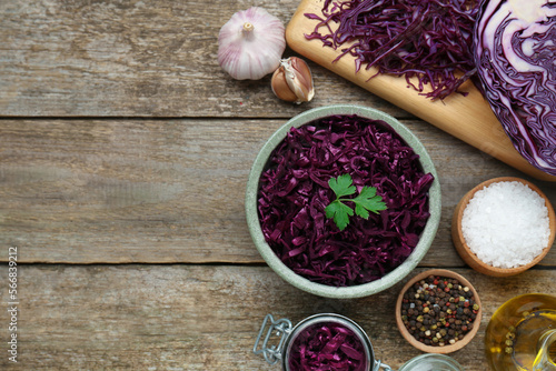 Tasty red cabbage sauerkraut with parsley and different ingredients on wooden table, flat lay. Space for text