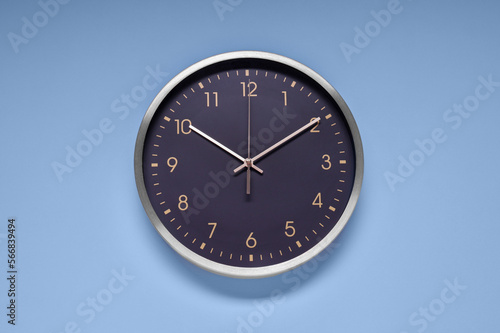 Stylish round clock on light blue background, top view. Interior element