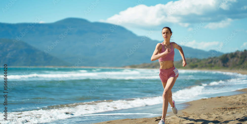 Sports fit runner jogging outdoors on beautiful tropical seashore with mountains view. Running woman healthy lifestyle