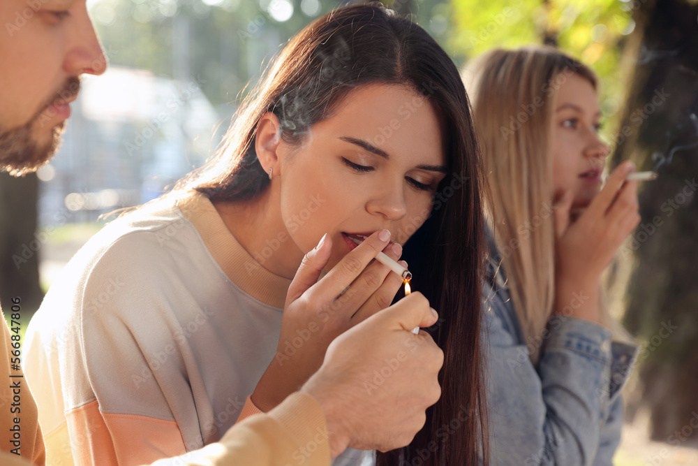 People smoking cigarettes outdoors on sunny day People smoking cigarettes outdoors on sunny day