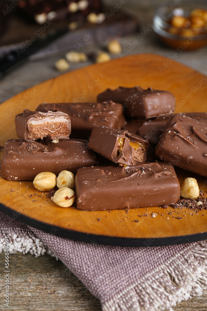 Delicious chocolate candy bars with nuts on wooden table, closeup Delicious chocolate candy bars with nuts on wooden table, closeup