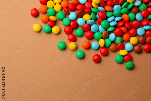 Tasty colorful candies on light brown background, above view. Space for text