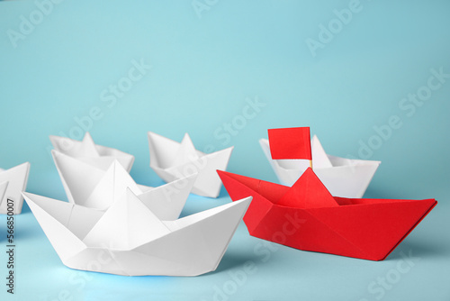 Red paper boat among others on light blue background. Uniqueness concept