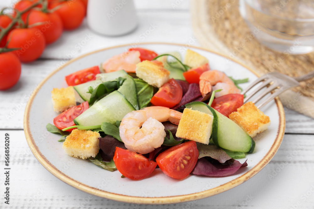 Tasty salad with croutons, tomato and shrimps served on white wooden table, closeup