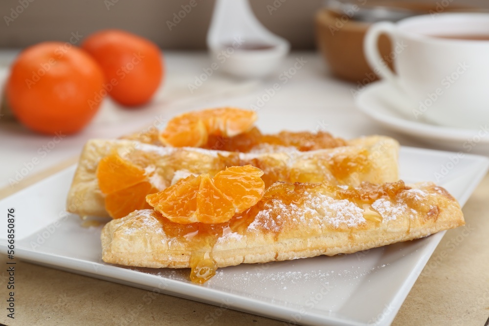 Fresh tasty puff pastry with sugar powder and tangerines on table, closeup Fresh tasty puff pastry with sugar powder and tangerines on table, closeup
