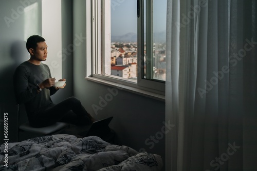 Asian man is having breakfast by the windows in the apartment. © Sevendeman