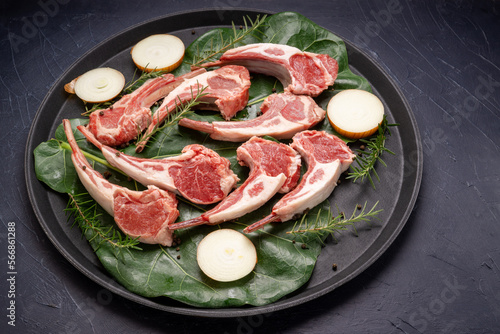 Lamb chops with rosemary and onion in black plate on wooden background, Fresh Raw lamb loin on black Background.