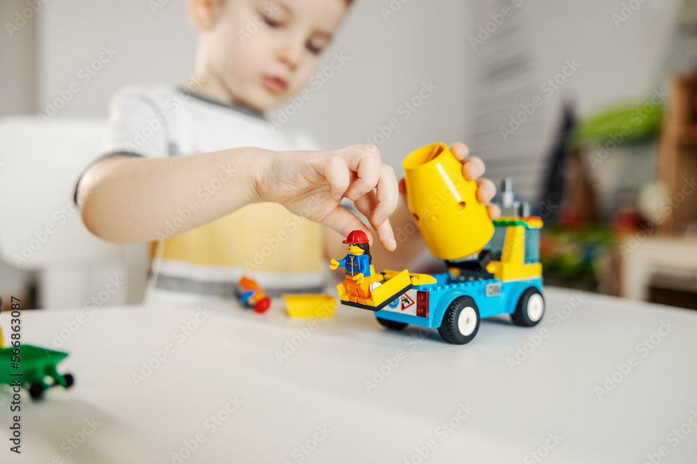 Obraz premium Selective focus on a boy playing a game and having fun with vehicle toy while sitting in his room.