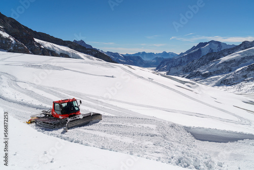 An enormous red snow plow moves along the glacial surface at Jungfraujoch
