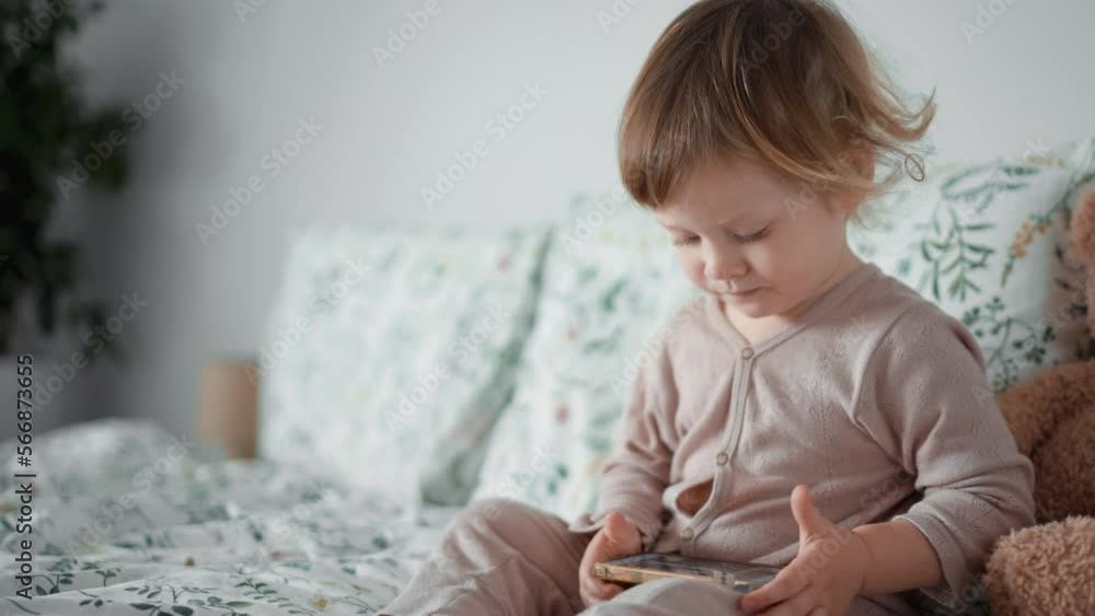 Cute sweet boy tap on phone screen of mobile smartphone. Little toddler play educational mobile games. Concept of modern technology, online education. Baby watching cartoon, study how to use gadget Cute sweet boy tap on phone screen of mobile smartphone. Little toddler play educational mobile games. Concept of modern technology, online education. Baby watching cartoon, study how to use gadget