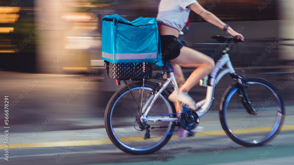 Unrecognizable young woman doing delivery on a bicycle with motion blur. Unrecognizable young woman doing delivery on a bicycle with motion blur.