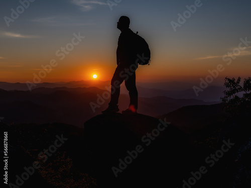 Young Man standing alone in forest outdoor with sunset nature on background Travel Lifestyle and survival concept.