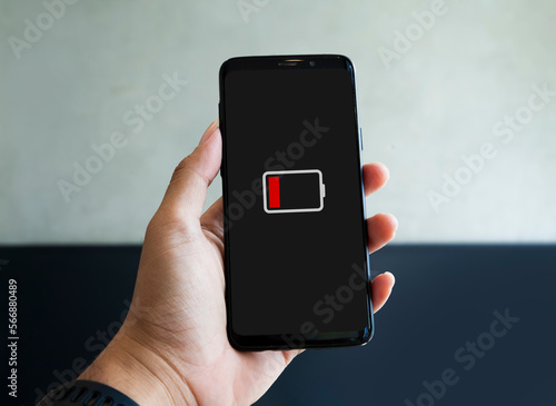 Φωτογραφία Close up of hand holding smart phone with low battery icon on screen