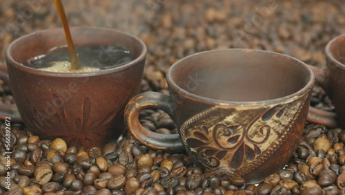 A cup of hot coffee stands on the table next to coffee beans. Cinnamon sticks for coffee are very tasty. Coffee beans background for advertising. photo