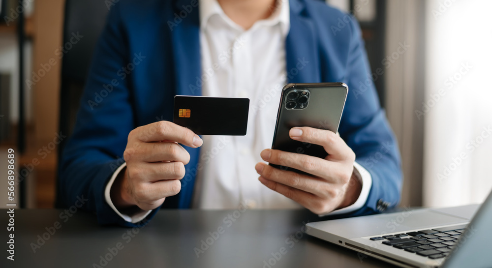 Man using smart phone for mobile payments online shopping,omni channel,sitting on table,virtual icons graphics interface screen Man using smart phone for mobile payments online shopping,omni channel,sitting on table,virtual icons graphics interface screen
