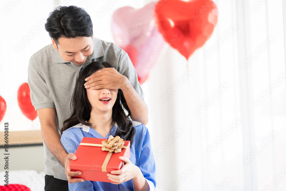 Asian couple Showing love surprise giving flowers or gifts to each other on important occasions such as Valentine's Day birthdays or wedding anniversaries with love and warmth in bedroom of their home Asian couple Showing love surprise giving flowers or gifts to each other on important occasions such as Valentine's Day birthdays or wedding anniversaries with love and warmth in bedroom of their home