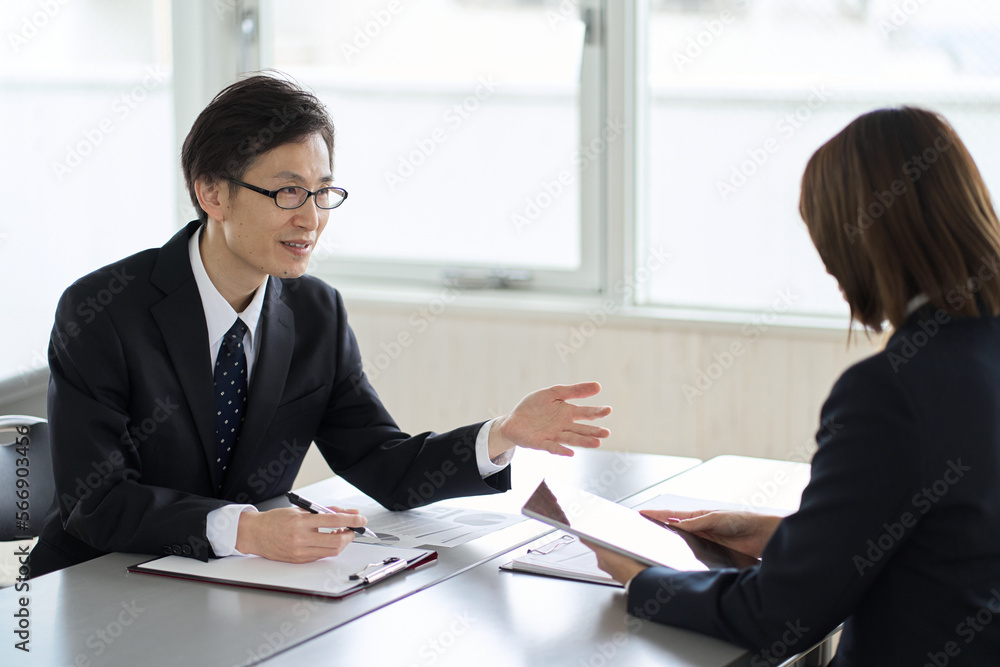 タブレットを見せて説明するアジア人ビジネスパーソン