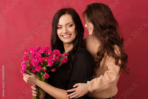 The girl greets her mother with a beautiful bouquet of pink roses on a Viva Magenta color background