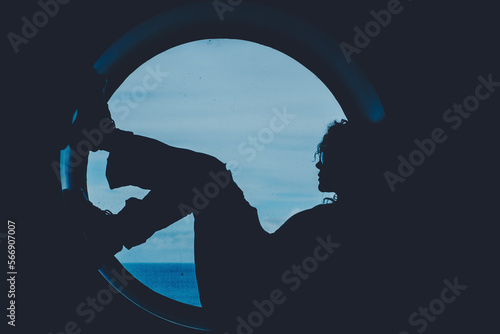 Silhouette of a woman boat passenger having relax sitting on a big window porthole with sea ocean waves in background outside. People in travel trip lifestyle. Transport on the ocean. Wanderlust