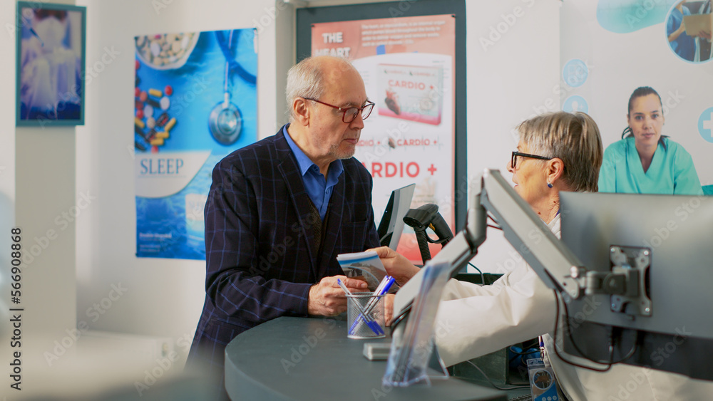 Obraz premium Senior adult talking to pharmacist at cash register counter, using medical leaflet to ask about healthcare treatment. Customer standing at pharmacy desk before buying products.