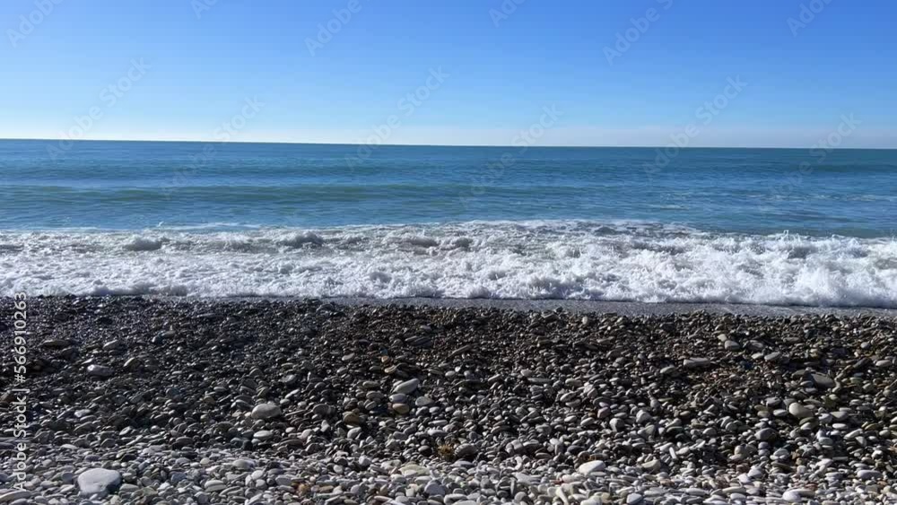 Powerful sea waves are crashing on the Black Sea coast. Sea waves splash on the beach with pebbles in the rays of the sun. Russia, Agoi Powerful sea waves are crashing on the Black Sea coast. Sea waves splash on the beach with pebbles in the rays of the sun. Russia, Agoi