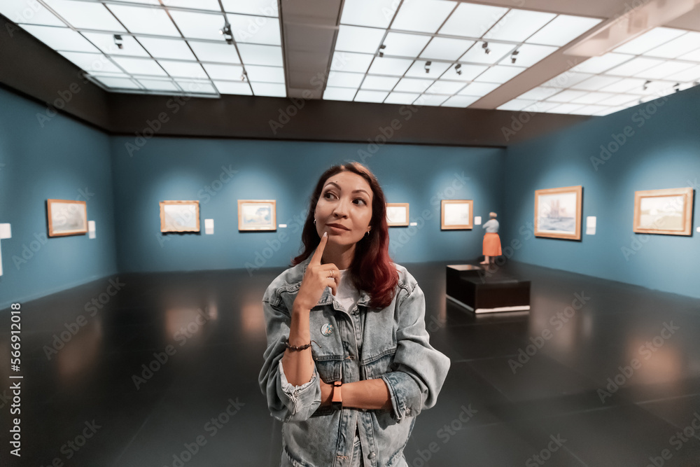 girl critic and expert visitor to a museum or art gallery thoughtfully looks at and evaluates artworks and classical paintings
