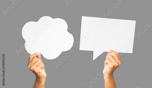 Close-up of hands holding a white speech bubbles against a gray background