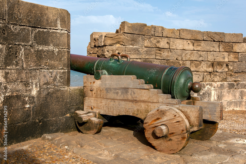 A bronze cannon made at Barcelona in Spain located at the former fortress at Essaouira in Morocco. It faces towards the Atlantic Ocean. The cannon sits on a wooden gun carriage with wooden wheels.