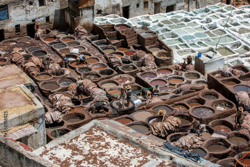Men working in the chemical pools at the famous Chouara Tannery in the Fez medina in Morocco. The leather tannery dates back to the 11th century AD. The medina is the oldest walled part of Fez.